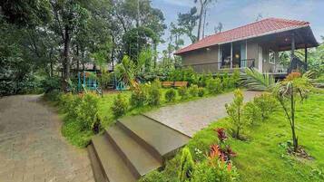 A resort with a red-roofed building, surrounded by lush greenery and a paved pathway leading to the entrance.