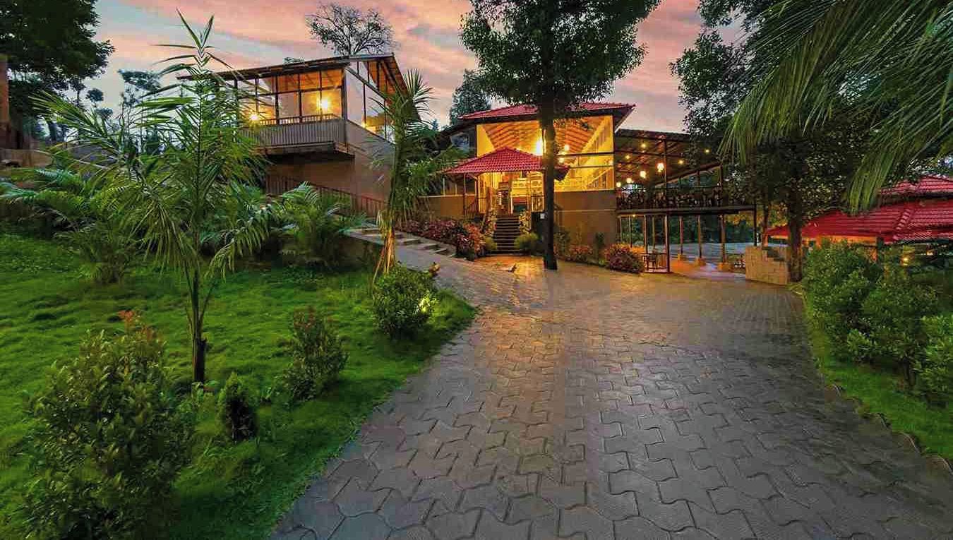 Un resort con un camino pavimentado que lleva a un edificio con techo rojo y ventanas de vidrio.