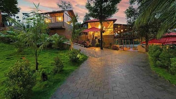 A resort with a paved pathway leading to a building with a red roof and glass windows.