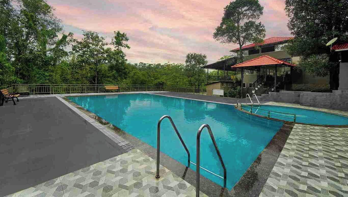 Una piscina con un borde de baldosas, una zona de estar techada y un pabellón.