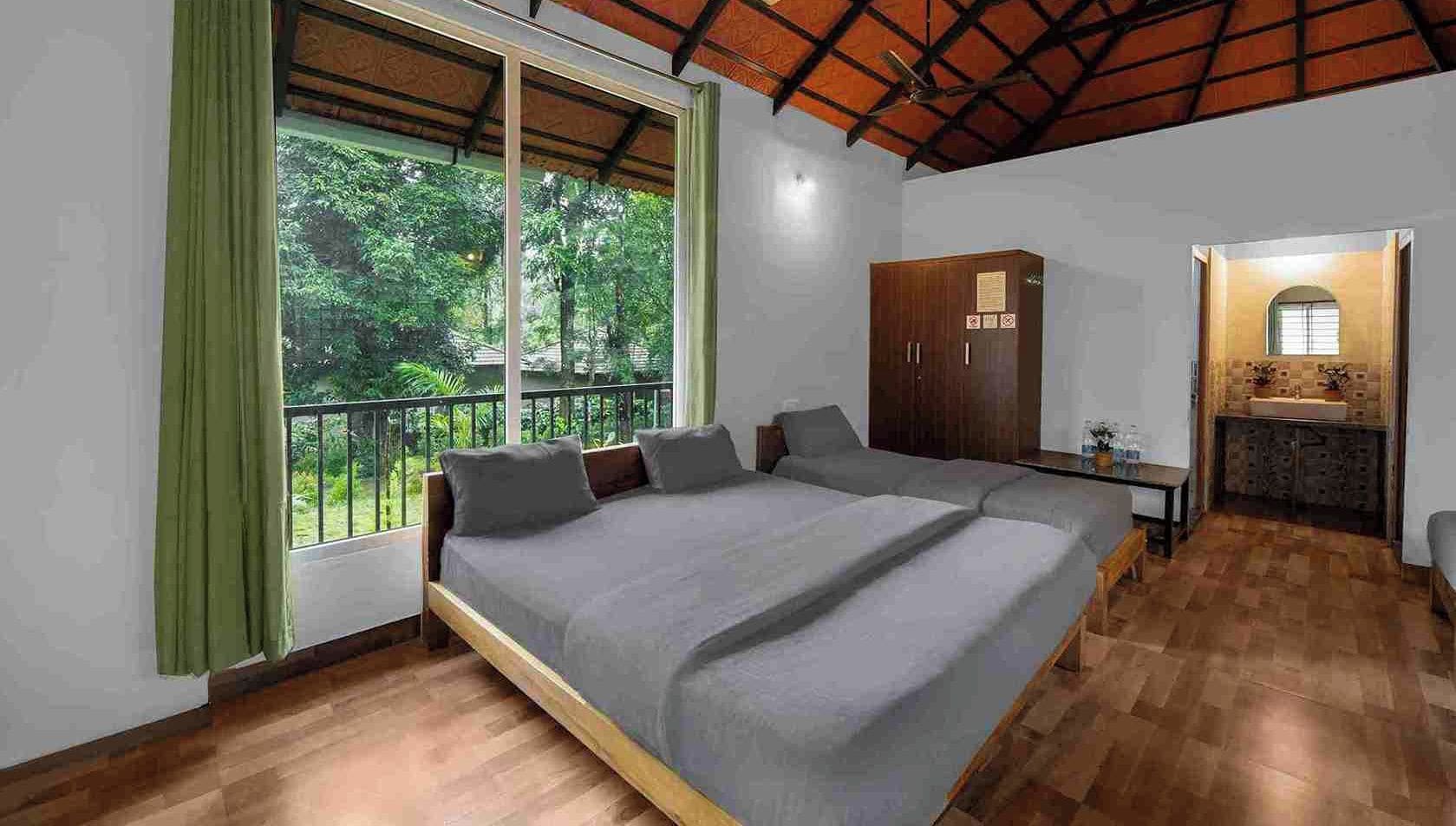 Un dormitorio con una cama grande, un armario, una mesita y vistas a zonas verdes a través de una ventana.