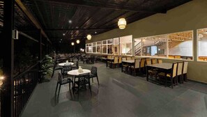 A spacious restaurant with high ceilings and modern lighting, featuring multiple dining areas with tables and chairs. - Abbi Valley Resorts  (Sakleshpur)