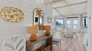 A spacious room with a large mirror, two lamps, wicker chairs, a white sofa, and a view of the sea. - Experience luxury at SeaSons at the Point, a stunning oceanfront rental in Oak Island. (Oak Island)