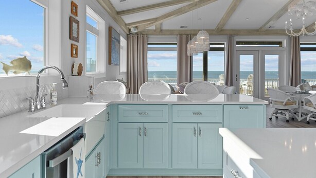 A modern kitchen with a large island, white cabinetry, and a view of the ocean. - Experience luxury at SeaSons at the Point, a stunning oceanfront rental in Oak Island. (Oak Island)