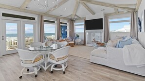 A spacious living room with a large window, a fireplace, and a balcony with a view of the sea. - Experience luxury at SeaSons at the Point, a stunning oceanfront rental in Oak Island. (Oak Island)