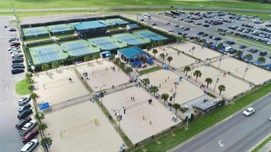 An aerial view of a sports complex with multiple tennis courts, a covered seating area, and a parking lot. - New  Extra Innings Cottage - Studio - Sports Complex (Youngsville)