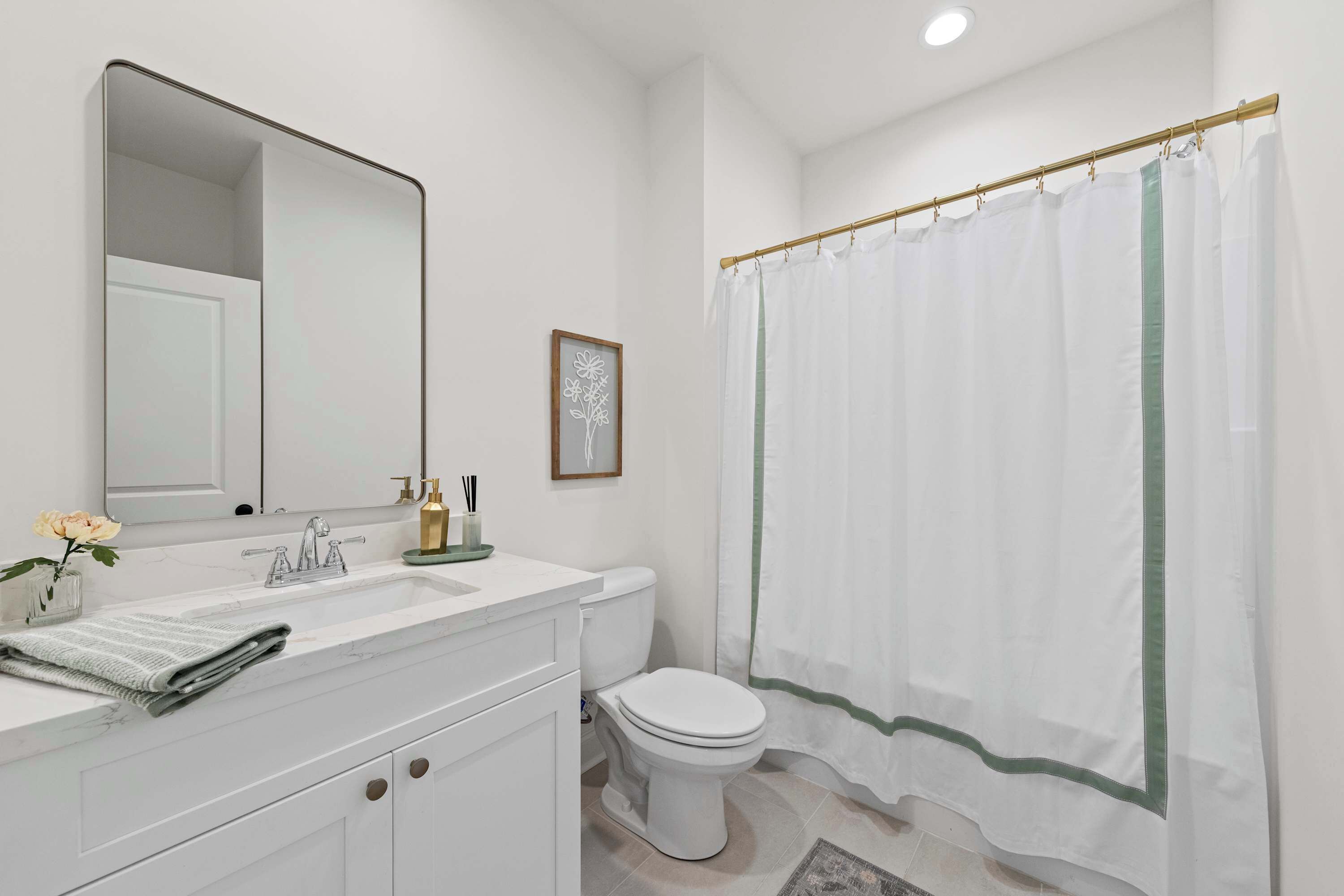 Een moderne badkamer met een witte wastafel, een grote spiegel, een toilet en een douchegordijn.