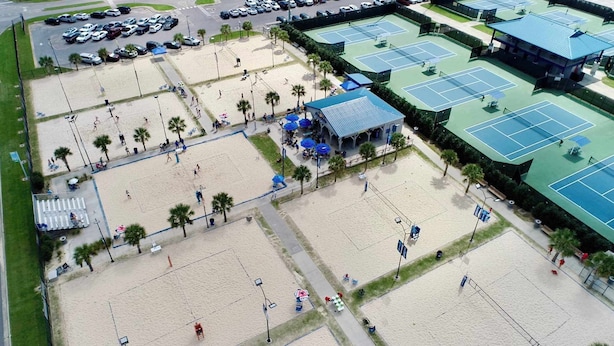 Oversigtsbillede af et strandområde med flere tennisbaner, et overdækket siddeområde og en parkeringsplads.