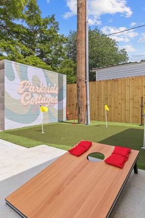 Un tavolo di legno con cuscini rossi, un cartello con la scritta 'Parkside Cottages' e una recinzione in legno sullo sfondo.