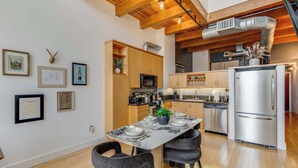 A modern kitchen with wooden beams, stainless steel appliances, and a dining area set for four. - Santana Row Properties #9 - Silicon Valley Getaway: Escape the Ordinary! (San Jose)