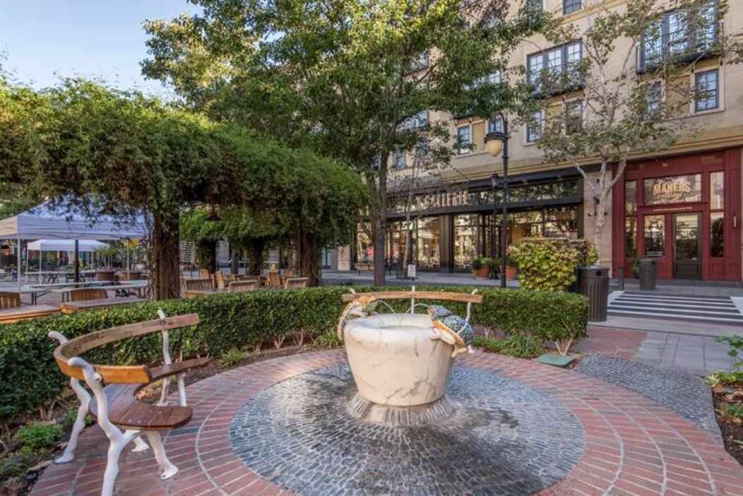 Une cour intérieure avec une fontaine centrale, des bancs et un bâtiment doté d’une vitrine.