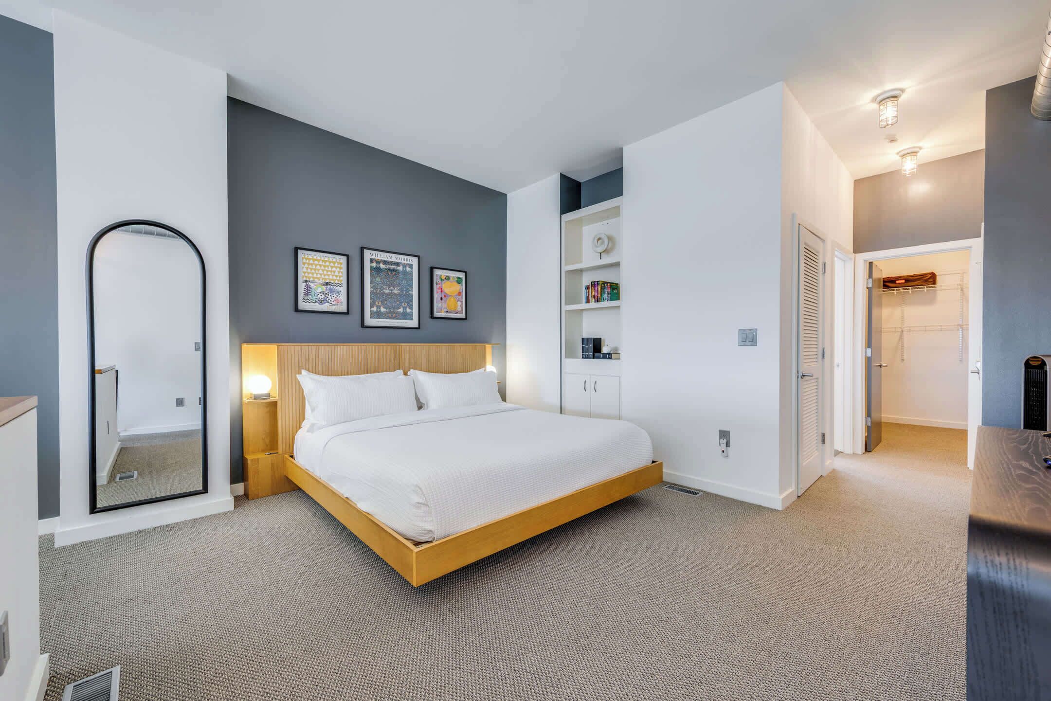 Une chambre moderne avec un grand lit, une table de chevet, un miroir et une armoire.