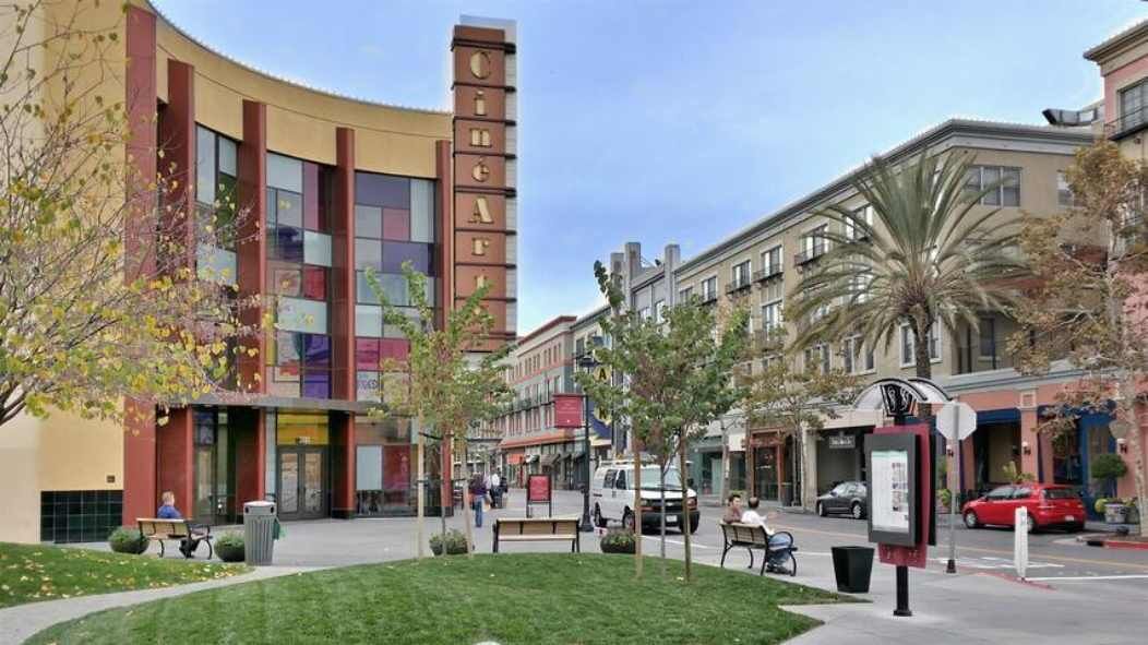 A multi-story building with a prominent 'CINEMA' sign, surrounded by a pedestrian area with benches and trees.