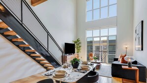 A modern dining area with a staircase, a flat-screen TV, and a dining table set for four. - Santana Row Properties #9 - Silicon Valley Getaway: Escape the Ordinary! (San Jose)