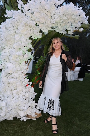 A person standing in front of a white floral archway.