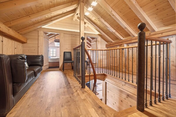 Un interior de madera con una escalera, un sofá de cuero y un televisor.
