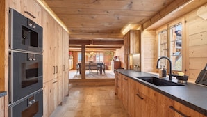 Een moderne keuken met houten kastjes, roestvrijstalen apparatuur en een centraal keukenblok met een spoelbak.