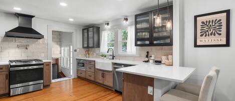 A modern kitchen with a central island, stainless steel appliances, wooden cabinets, and pendant lighting.