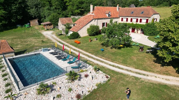 Una piscina grande con tumbonas y un jardín con un camino empedrado.