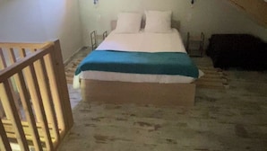 Un dormitorio pequeño estilo ático con una cama individual, una silla de madera y techo inclinado.