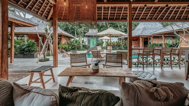 An outdoor seating area with wooden furniture, a pool, and a covered patio.