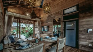 A wooden interior with a dining table set for four, surrounded by wicker chairs.