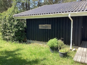 A wooden shed with a corrugated metal roof, a sign reading 'Federen,' and potted plants in front.