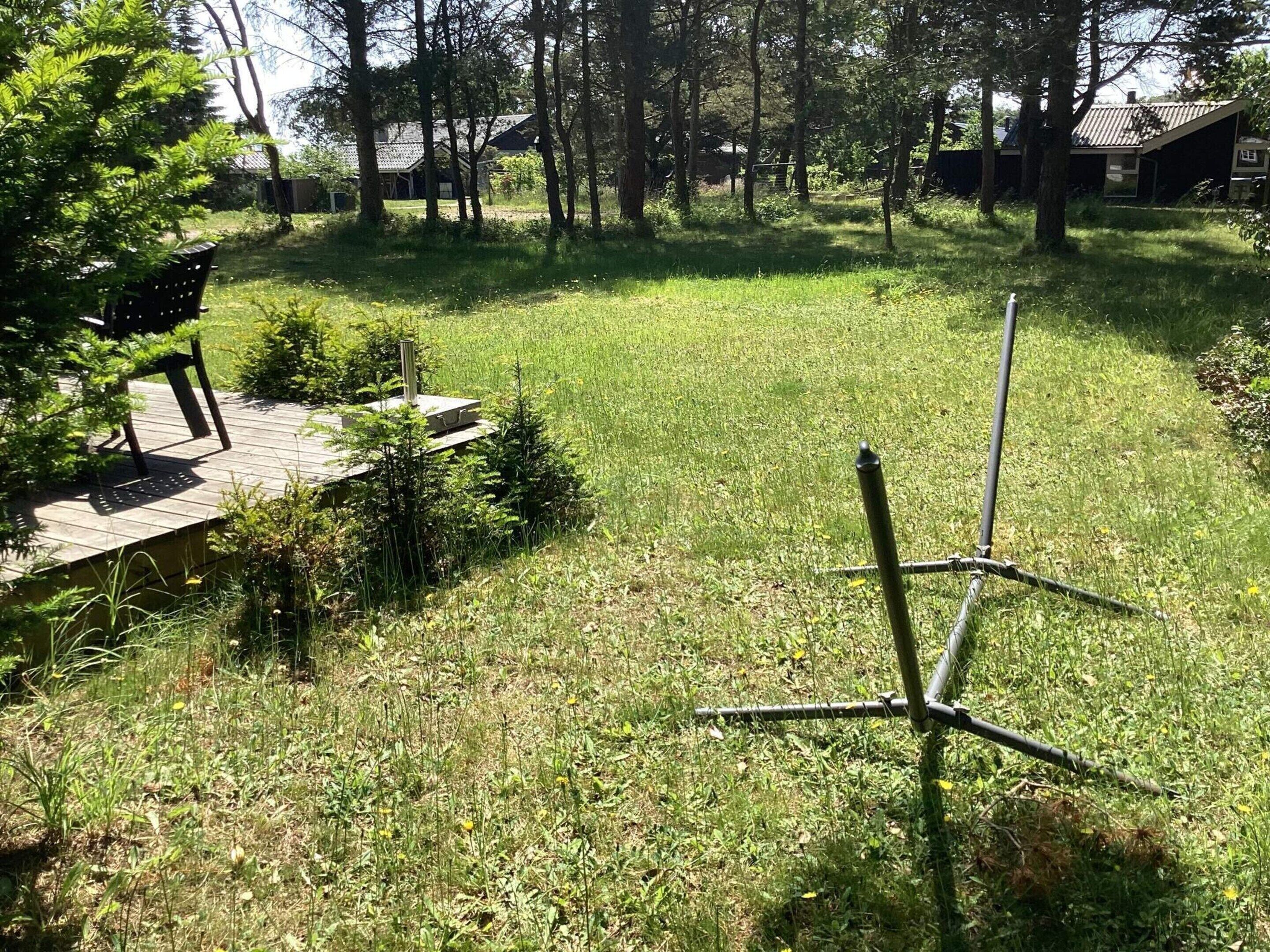 Een gazon met een houten terras en een constructie van metalen palen.