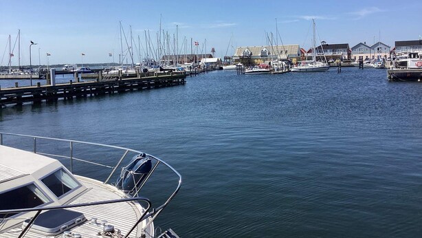 A marina with boats docked, a pier extending into the water, and buildings in the background. - 6 Person Holiday Home in Hals (Hals)