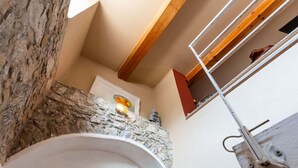 A bathroom with a stone wall, a white sink, and a wooden ceiling beam.