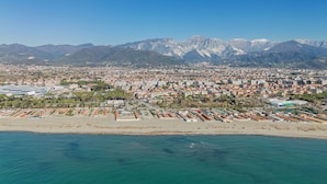 A coastal cityscape with a beach, residential buildings, and mountains in the background.