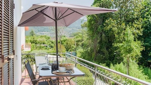 A balcony with a table, chairs, and a large umbrella.