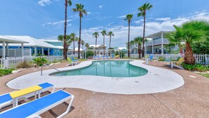 A pool area with lounge chairs, palm trees, and a white fence. - FD186 Shared Pool, Pet Friendly, Golf Cart Included, Boardwalk to the Beach (Port Aransas)