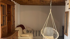A room with a hanging chair, a sofa, and a wooden cabinet.