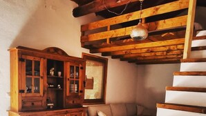 A staircase with wooden steps leading to a landing area with a sofa and a wooden cabinet with glass doors.