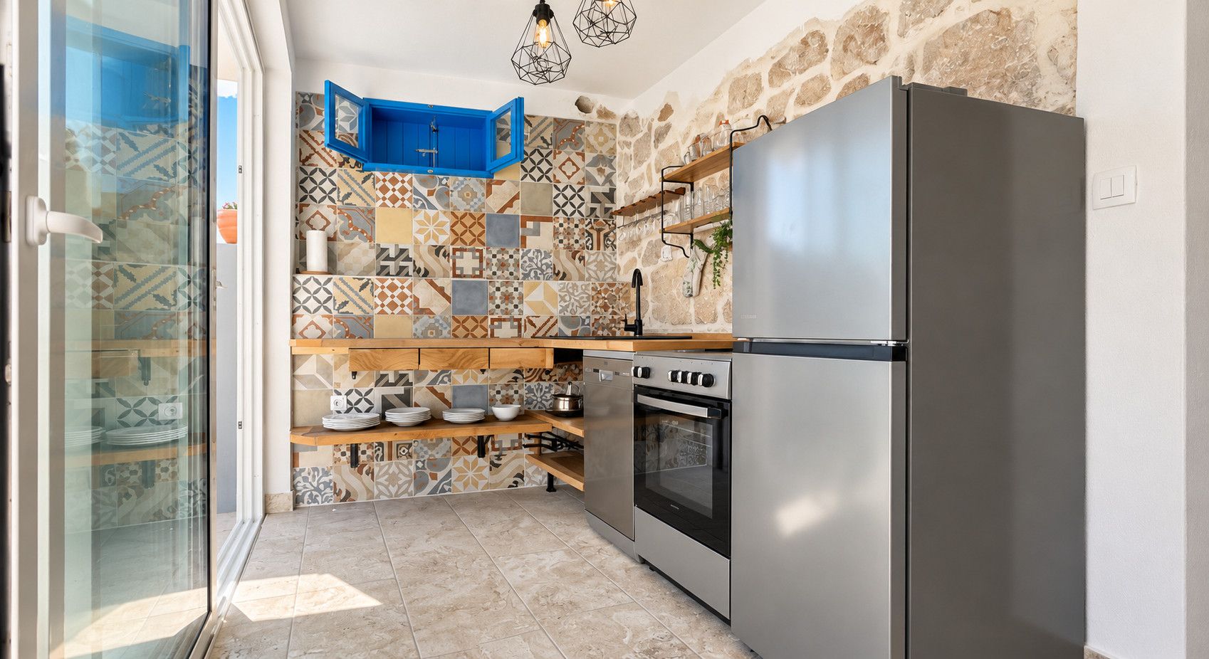 A kitchen with a modern stainless steel refrigerator, an oven, and a blue cabinet.