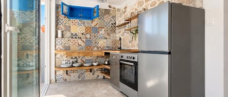 A kitchen with a modern stainless steel refrigerator, an oven, and a blue cabinet.