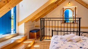 A bedroom with a wooden staircase, a bed with rolled towels, a bench, and a view through a blue door. - Holiday Home Cherry with pool (Vrsine)