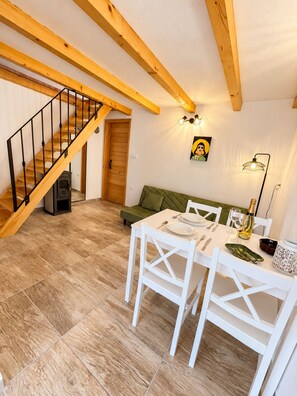 Un coin repas avec un escalier en bois, un canapé vert et une table mise pour deux personnes.
