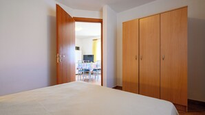 Une chambre à coucher avec un lit, une armoire en bois et une porte ouverte donnant sur un coin repas.