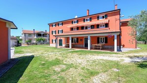 Un bâtiment à deux étages doté d’un patio couvert, d’un mur en pierre et d’une pelouse bien entretenue.