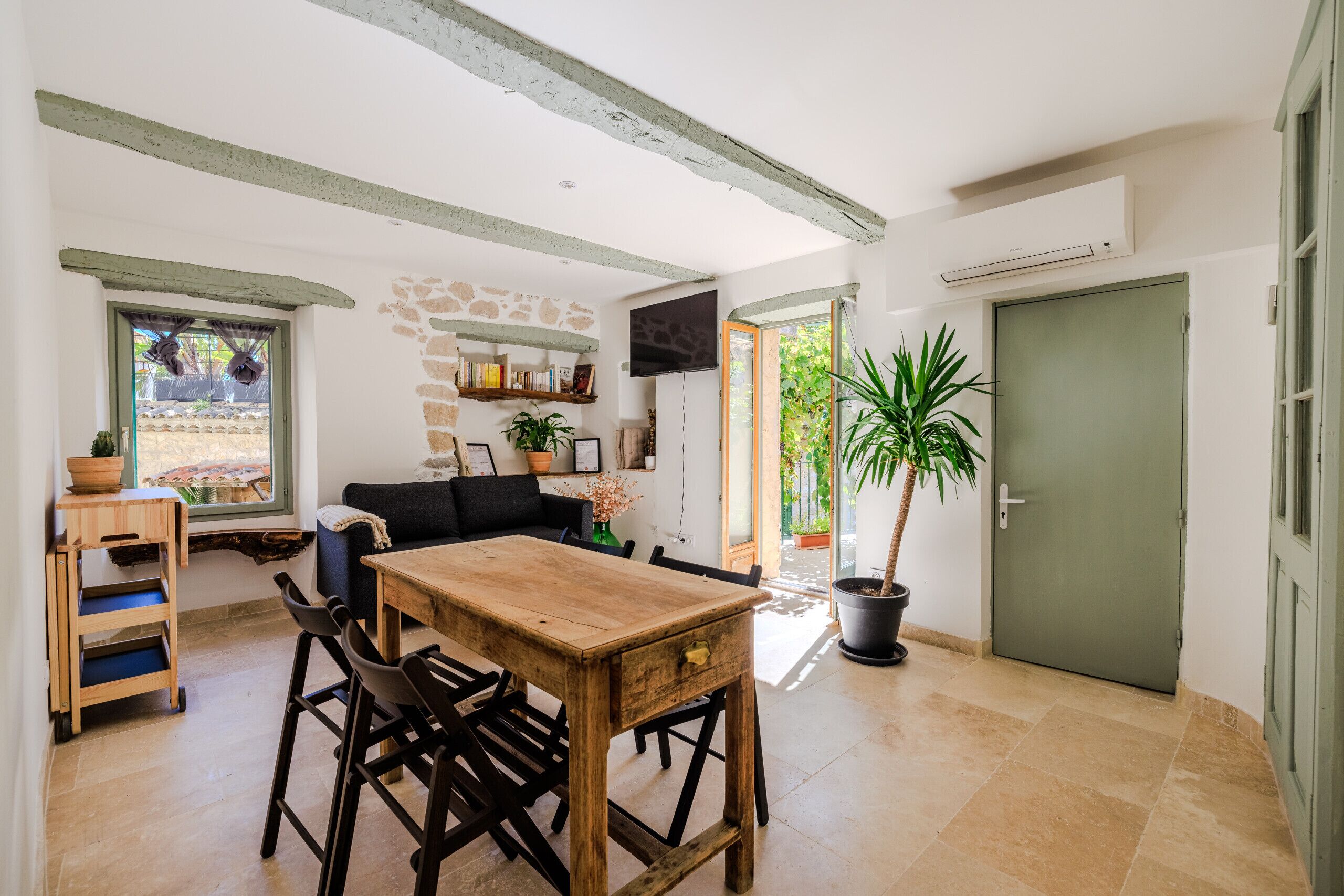 A cozy dining area with a wooden table and chairs, a stone wall, and a potted plant.