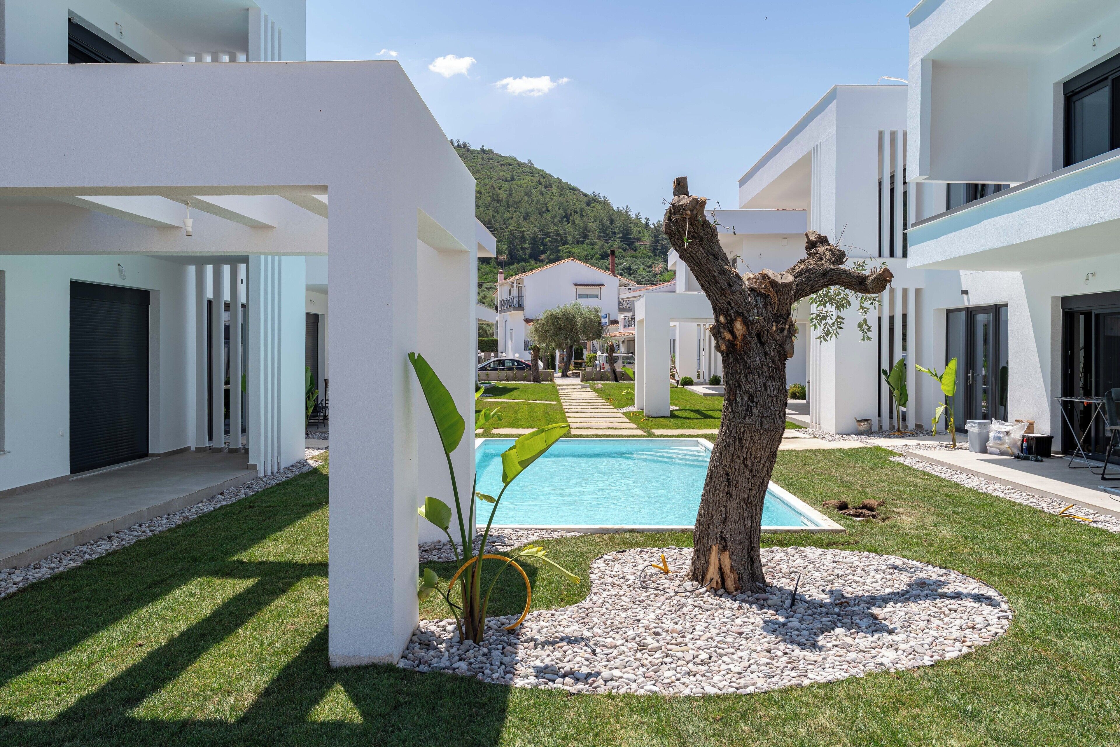 En moderne villa med swimmingpool, hvide facademuure og en velplejet have.