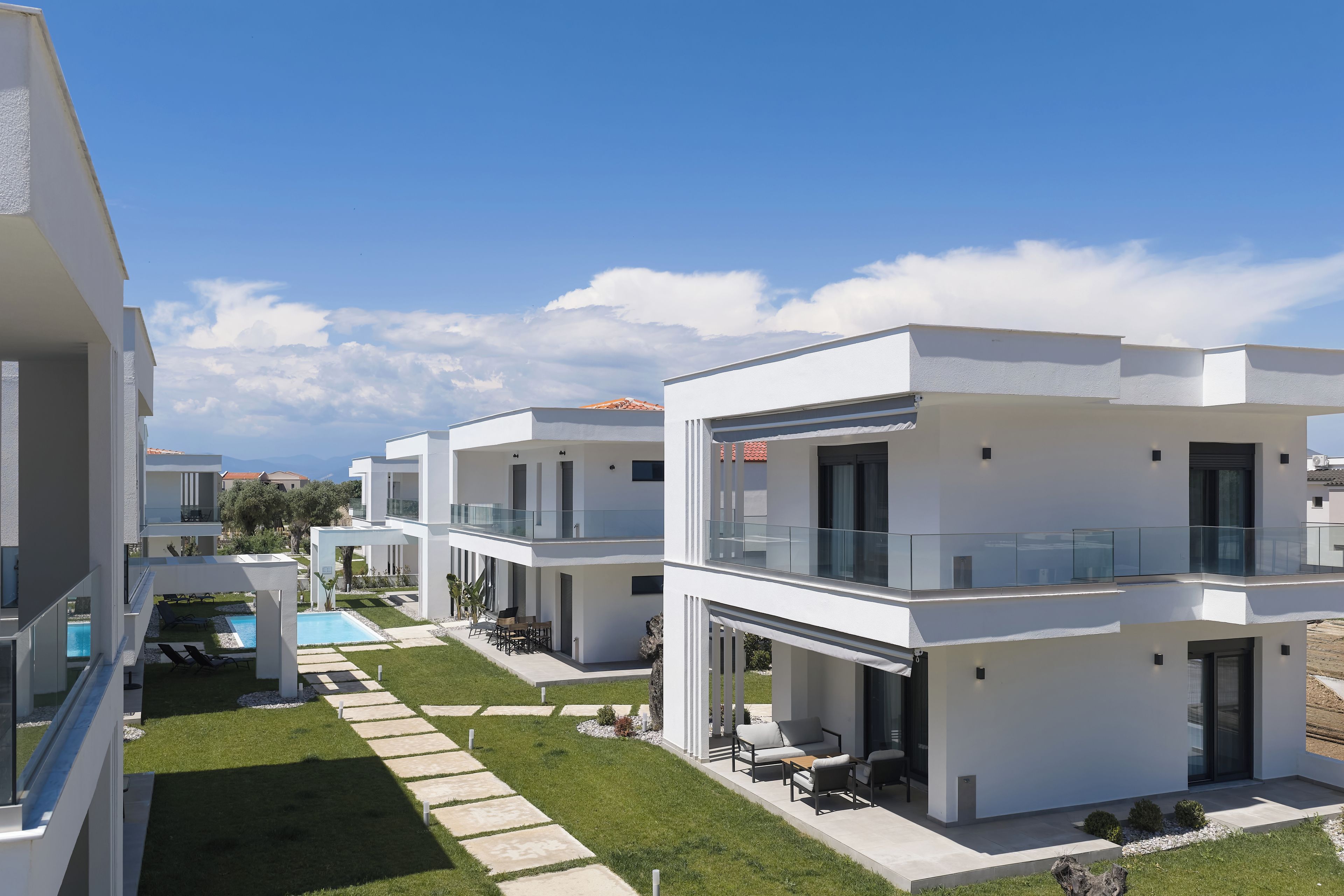 Um edifício residencial moderno com piscina, área de estar ao ar livre e céu claro.