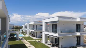 Um edifício residencial moderno com piscina, área de estar ao ar livre e céu claro.