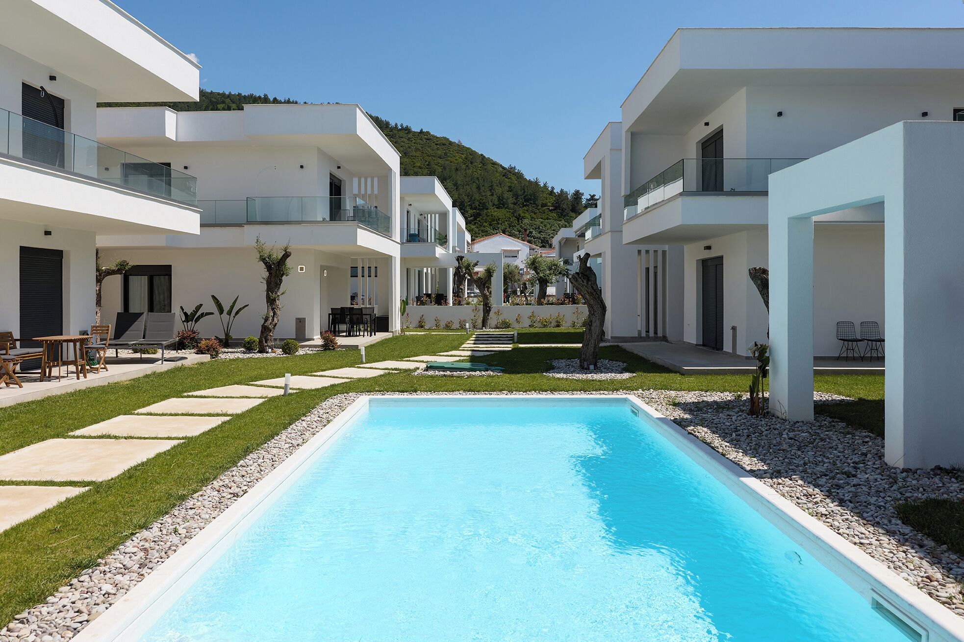 A modern resort with a central swimming pool, multiple balconies, and a well-maintained garden.
