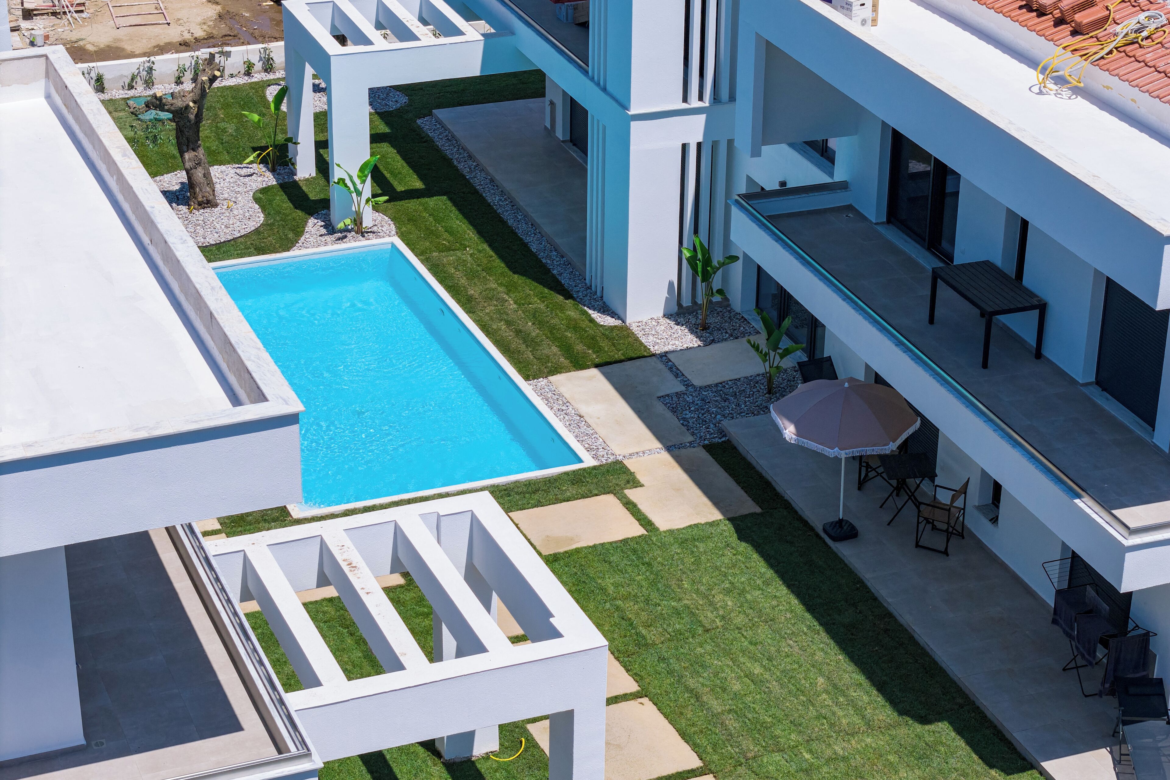 A modern building with a swimming pool, outdoor seating, and a well-maintained lawn.