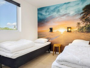 A hotel room with two beds, a view of the beach, and a sunset mural. - 5 Star Holiday Home in Spottrup (Spøttrup)