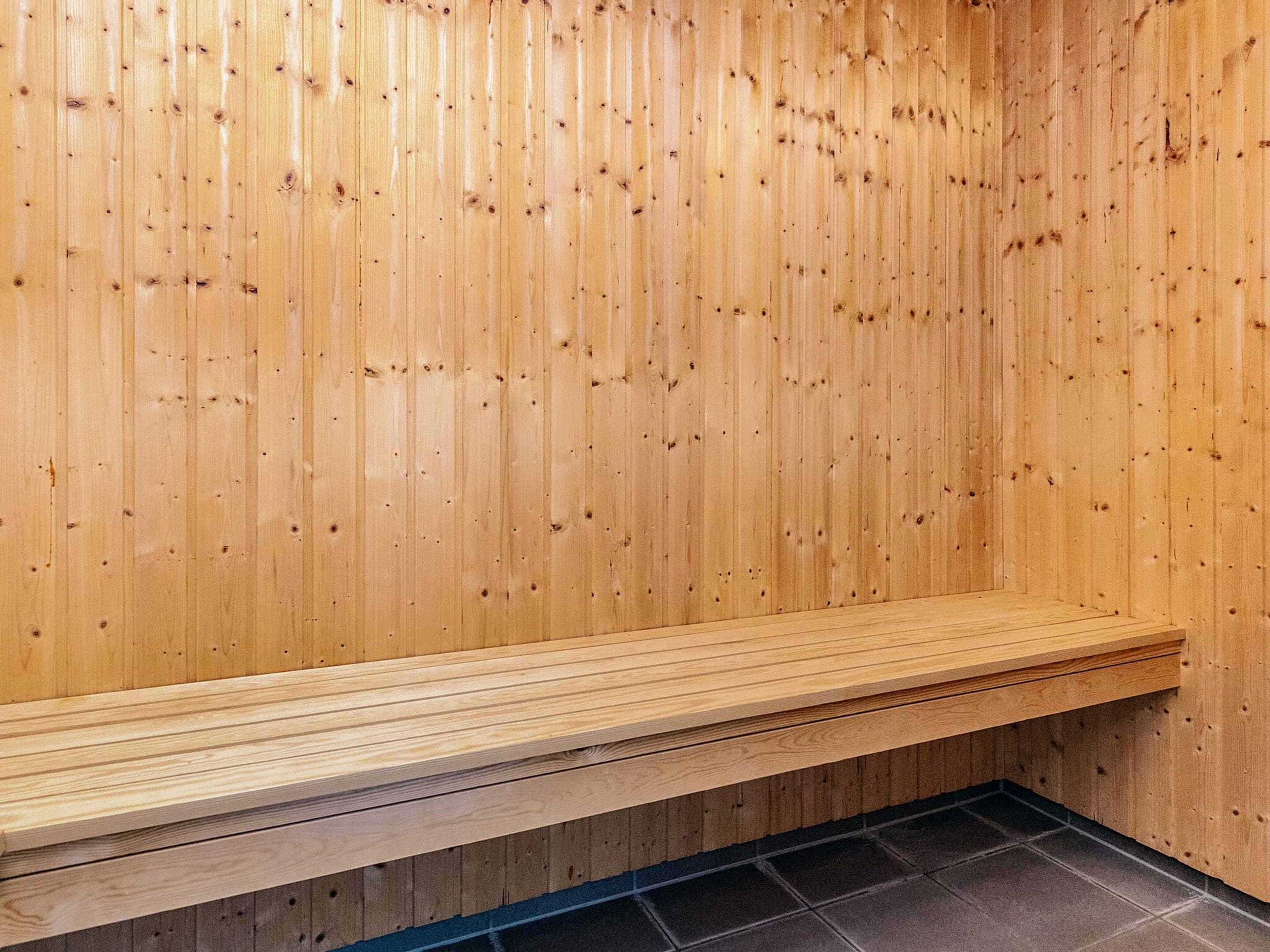 Un sauna avec des murs en bois et un banc.