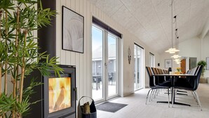 En modern inredning med en öppen spis, matplats och stora fönster.